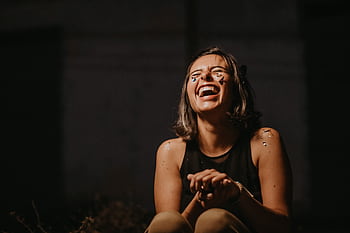A joyful young woman laughing with confetti on a dark background. HD wallpaper