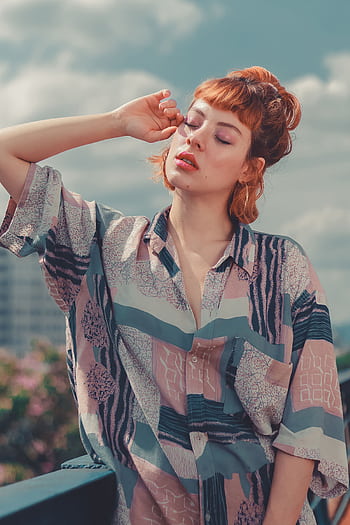 A fashionable young woman with red hair poses outdoors in a stylish patterned shirt on a sunny day. HD phone wallpaper