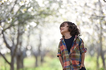 A joyful child in a colorful plaid shirt outdoors, enjoying a spring day. HD wallpaper