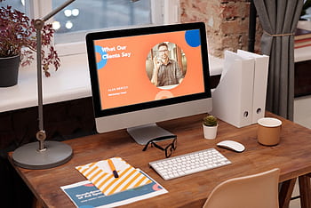 A modern home office setup with a computer displaying a client testimonial on the screen. HD wallpaper