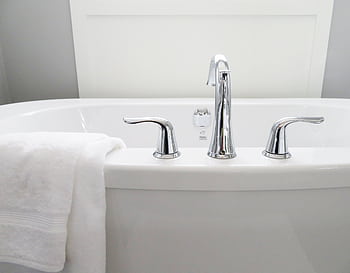 Clean and modern white bathtub with chrome fixtures, perfect for sleek interior design. HD wallpaper