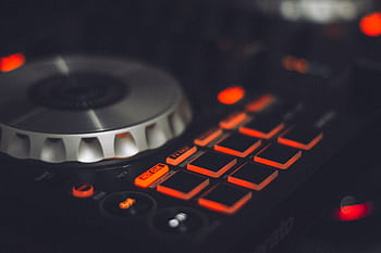Close-up of a DJ controller with illuminated buttons and control knobs, ideal for music technology themes. HD wallpaper