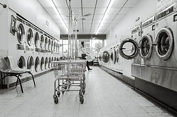 Black and white of a laundromat with laundry machines and a person in the background. HD wallpaper