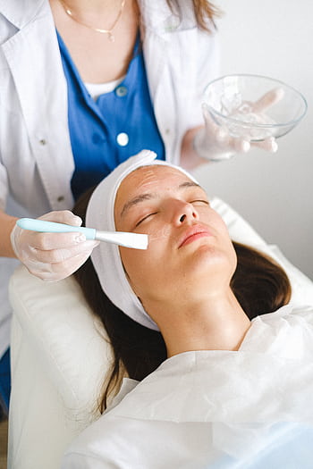 A woman receives a soothing facial treatment by a professional cosmetologist in a spa setting. HD phone wallpaper