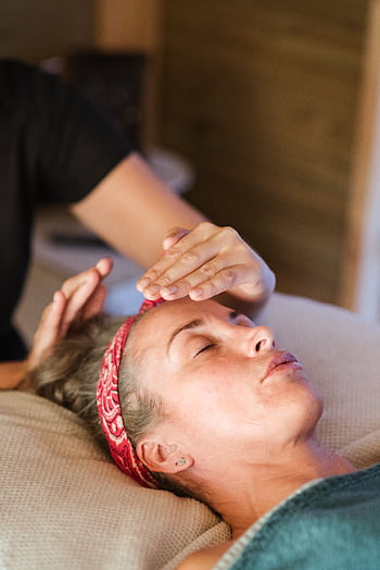 A woman enjoying a peaceful reiki session in a cozy spa setting for ultimate relaxation. HD phone wallpaper