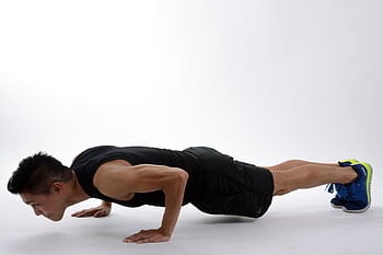 Young man in athletic wear doing push-ups, showcasing strength and fitness. HD wallpaper