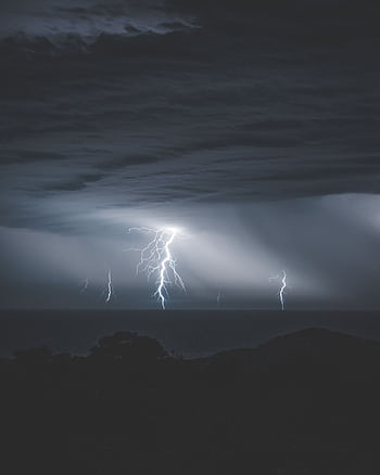 Captivating lightning bolts illuminate a dark stormy night above the ocean. HD phone wallpaper