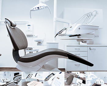 A modern dental clinic interior showcasing a dental chair and equipment in a clean, clinical setting. HD wallpaper