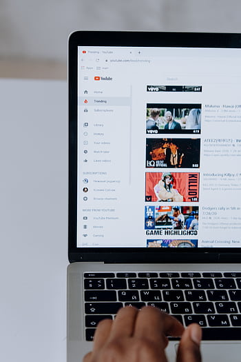 Person browsing YouTube videos on a laptop, showcasing modern technology and online content. HD phone wallpaper