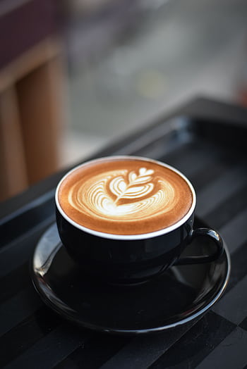 A beautifully crafted cappuccino with intricate latte art in a black ceramic mug on a dark surface. HD phone wallpaper