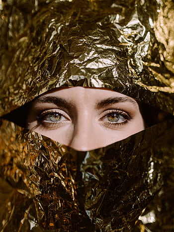 Elegant portrait of a woman partially concealed by gold foil, emphasizing her mysterious eyes. HD phone wallpaper
