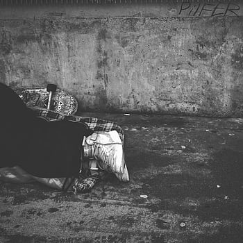 Black and white of a person sleeping on the sidewalk, depicting urban hardship. HD phone wallpaper