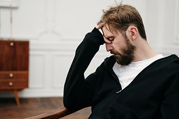 A man sits pensively with his hand on his face, capturing a moment of introspection and stress. HD wallpaper
