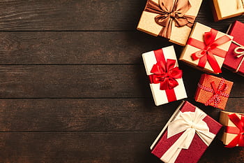 Beautifully wrapped holiday gifts with ribbons on a wooden surface, perfect for Christmas celebrations. HD wallpaper