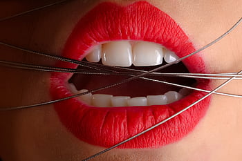 Artistic close-up of red-painted lips with metallic wire crossing the mouth. HD wallpaper