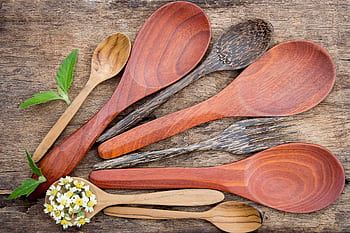 Top view of rustic wooden kitchen utensils and small flowers on a textured table. HD wallpaper