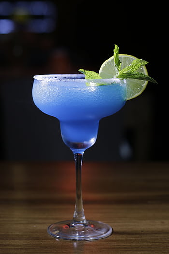 A vibrant blue margarita cocktail with lime and mint garnish on a wooden table. HD phone wallpaper