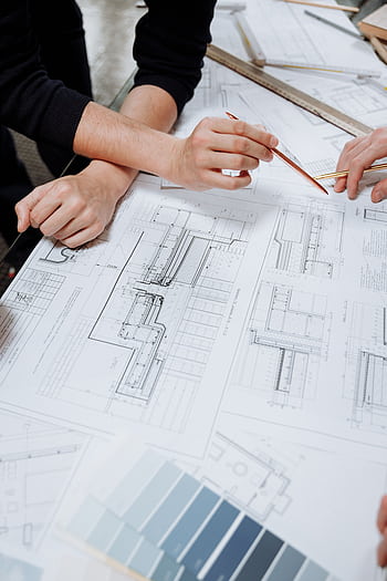 Architects discussing detailed blueprints and schematics at a table. HD phone wallpaper
