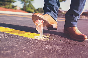 Close-up of a man's shoe getting stuck with chewing gum on the street, illustrating an everyday mishap. HD wallpaper