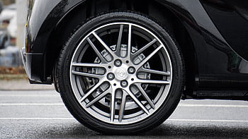Detailed shot of a sleek car wheel and rim on a black vehicle, showcasing automotive design. HD wallpaper