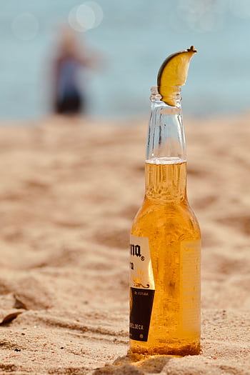 Chilled beer bottle with lime on sandy beach, perfect summer vibe. HD phone wallpaper