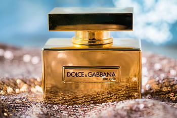 Golden perfume bottle with sequined background exudes luxury and elegance. HD wallpaper