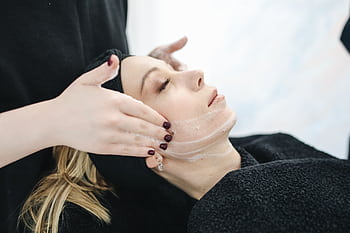 Side view of a woman receiving a soothing facial treatment at a spa, promoting wellness and skincare. HD wallpaper