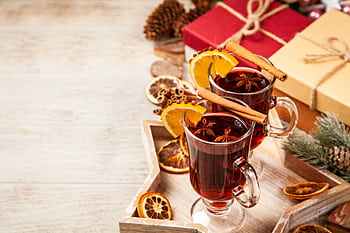 A cozy setup featuring mulled wine with cinnamon and orange slices, perfect for the holiday season. HD wallpaper