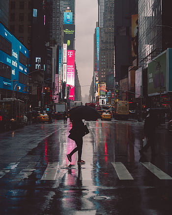 A person with an umbrella crossing Times Square at night, reflecting neon lights. HD phone wallpaper