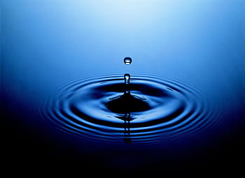Stunning close-up of a water drop creating ripples on a serene blue surface. HD wallpaper