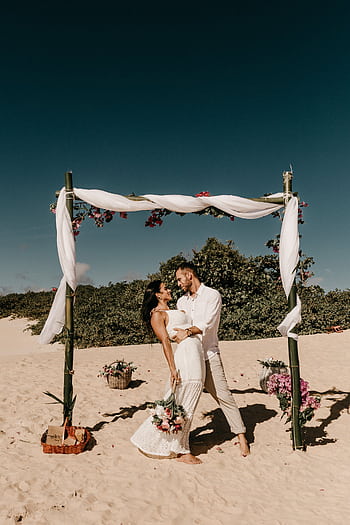 Beach wedding with couple under a decorated bamboo arch, capturing love and romance. HD phone wallpaper