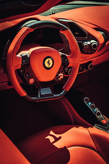 Close-up of a luxurious red interior of a sports car featuring a stylish steering wheel. HD phone wallpaper