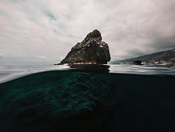 A Large Rock Sticking Out Of The Water, rock, nature HD wallpaper