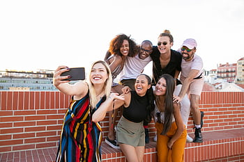 Cheerful group of diverse friends taking a selfie on a rooftop terrace in Portugal. HD wallpaper