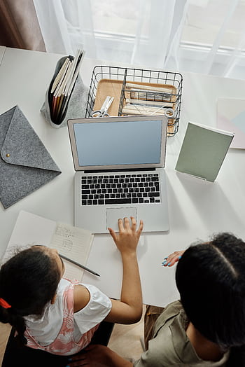 Overhead view of a mother helping her daughter with online learning at home. HD phone wallpaper