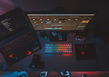 A contemporary workspace featuring dual monitors, a rainbow-lit keyboard, and editing software, perfect for tech enthusiasts. HD wallpaper
