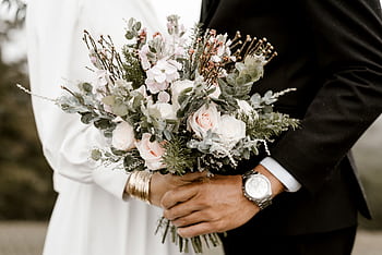 Close-up of a wedding bouquet held by bride and groom, showcasing romance and elegance. HD wallpaper