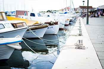 A collection of boats moored at a harbor pier on a clear day. Perfect for travel and maritime themes. HD wallpaper