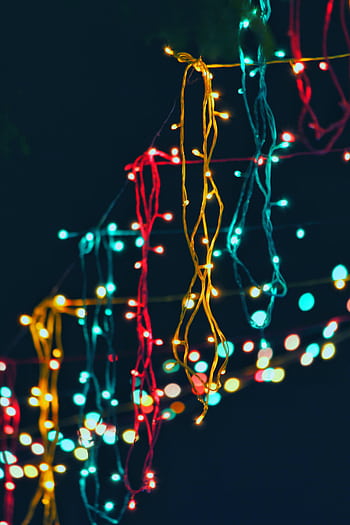Vibrant string lights hanging outdoors create a festive and colorful atmosphere at night. HD phone wallpaper