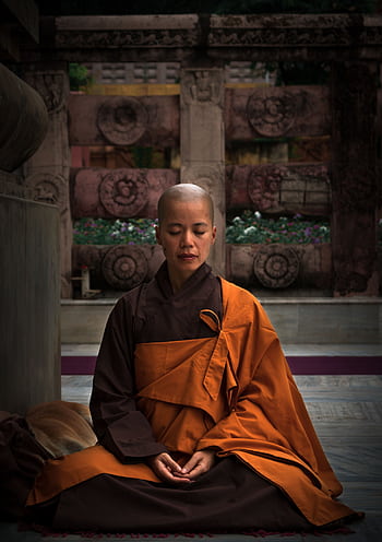 A monk meditating in a temple wearing traditional robes, embodying tranquility and spirituality. HD phone wallpaper