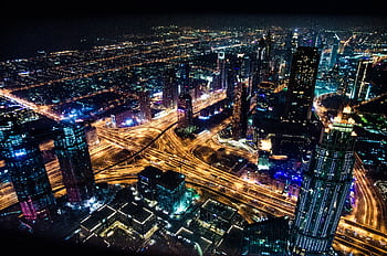 A stunning aerial view of Dubai's illuminated skyline at night, showcasing its modern architecture and busy roads. HD wallpaper