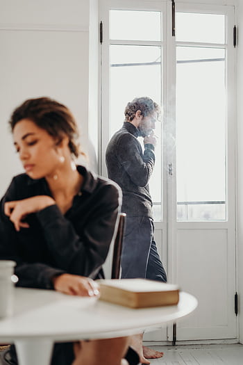 A couple experiencing tension and introspection indoors with a bright window. HD phone wallpaper