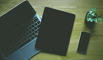 A top-down view of a workspace featuring a laptop, tablet, smart, and a small plant. HD wallpaper