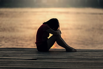 A woman sitting alone on a wooden dock by the lake, showing solitude and reflection. HD wallpaper