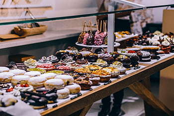 A tempting display of various donuts and pastries in a bakery. Ideal for food lovers and culinary enthusiasts. HD wallpaper