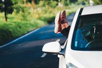 Man relaxing in car, scenic road trip in summer. Feet out window, enjoying countryside. HD wallpaper