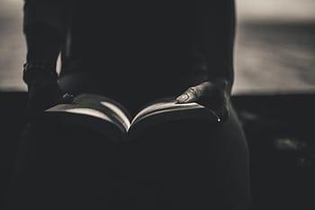 Silhouetted hands holding a book, creating a mysterious reading ambiance. HD wallpaper