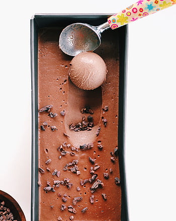 Delicious homemade chocolate ice cream in a tray with a colorful scoop, garnished with cacao nibs. HD phone wallpaper