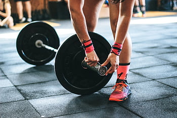 Athlete tightening barbell plates in a gym, emphasizing fitness and strength. HD wallpaper