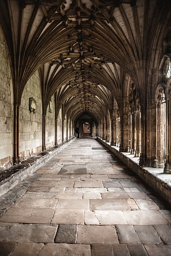 Explore the stunning gothic architecture of an ancient cloister corridor with intricate stone arches. HD phone wallpaper